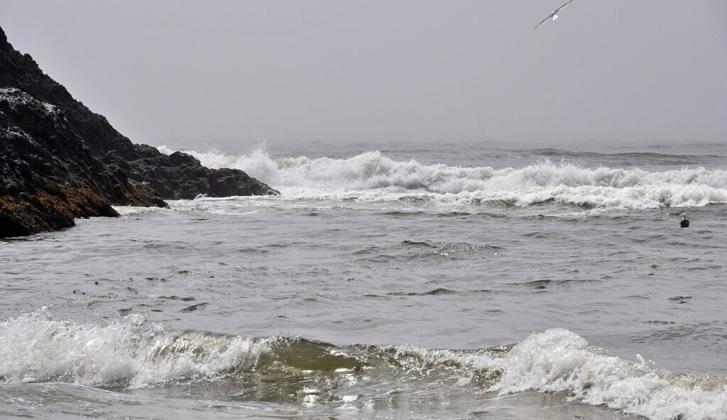 Onde che si frangono vicino a riva sollevando sabbia e schiuma lungo la battigia