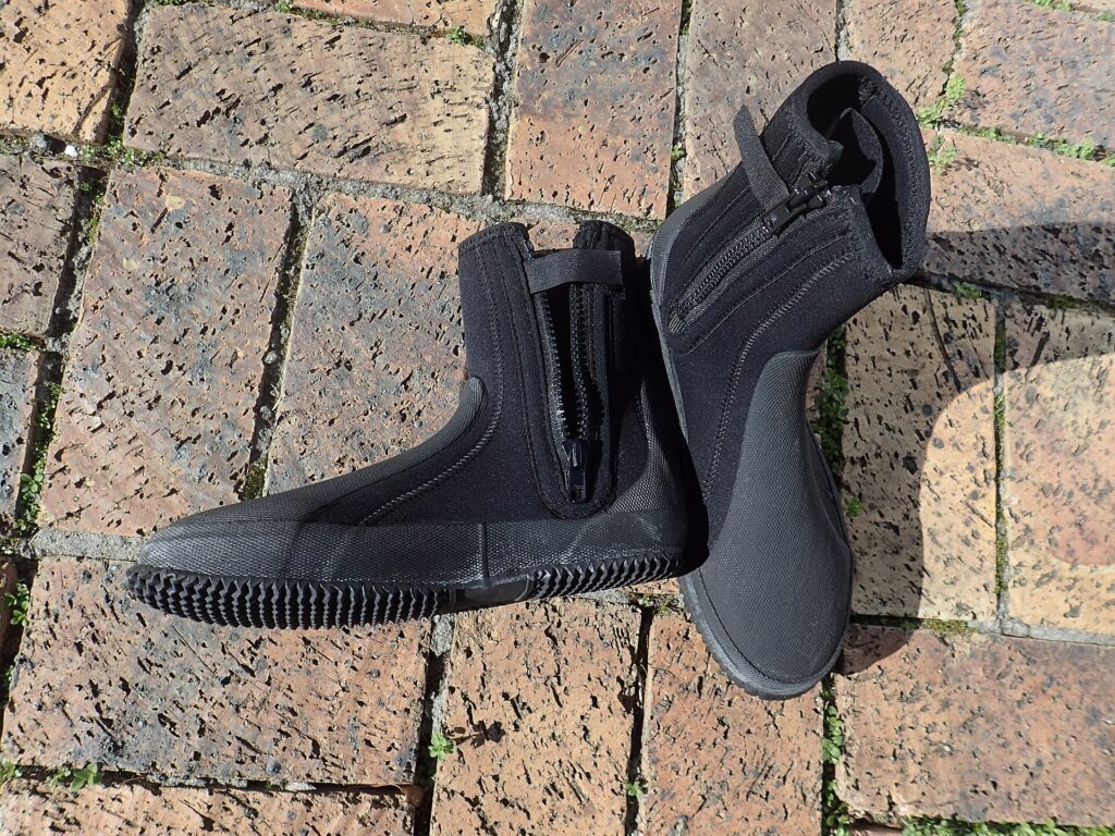 Muta in neoprene nera appesa ad asciugare accanto a una tavola da surf