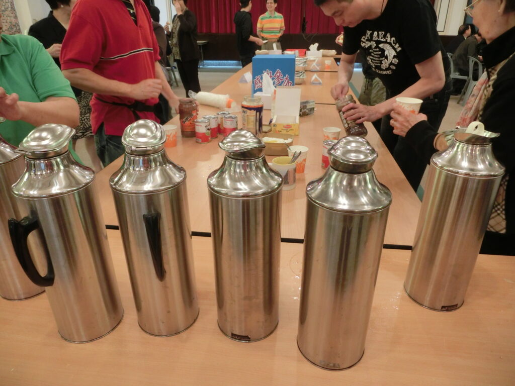 Thermos aperto e tazza fumante appoggiati su uno scoglio accanto a un asciugamano