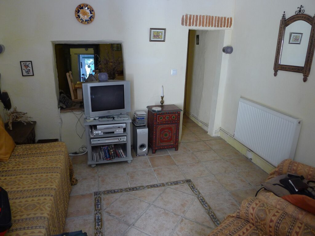Radiatore acceso sotto una finestra in una stanza spoglia con pavimento in piastrelle