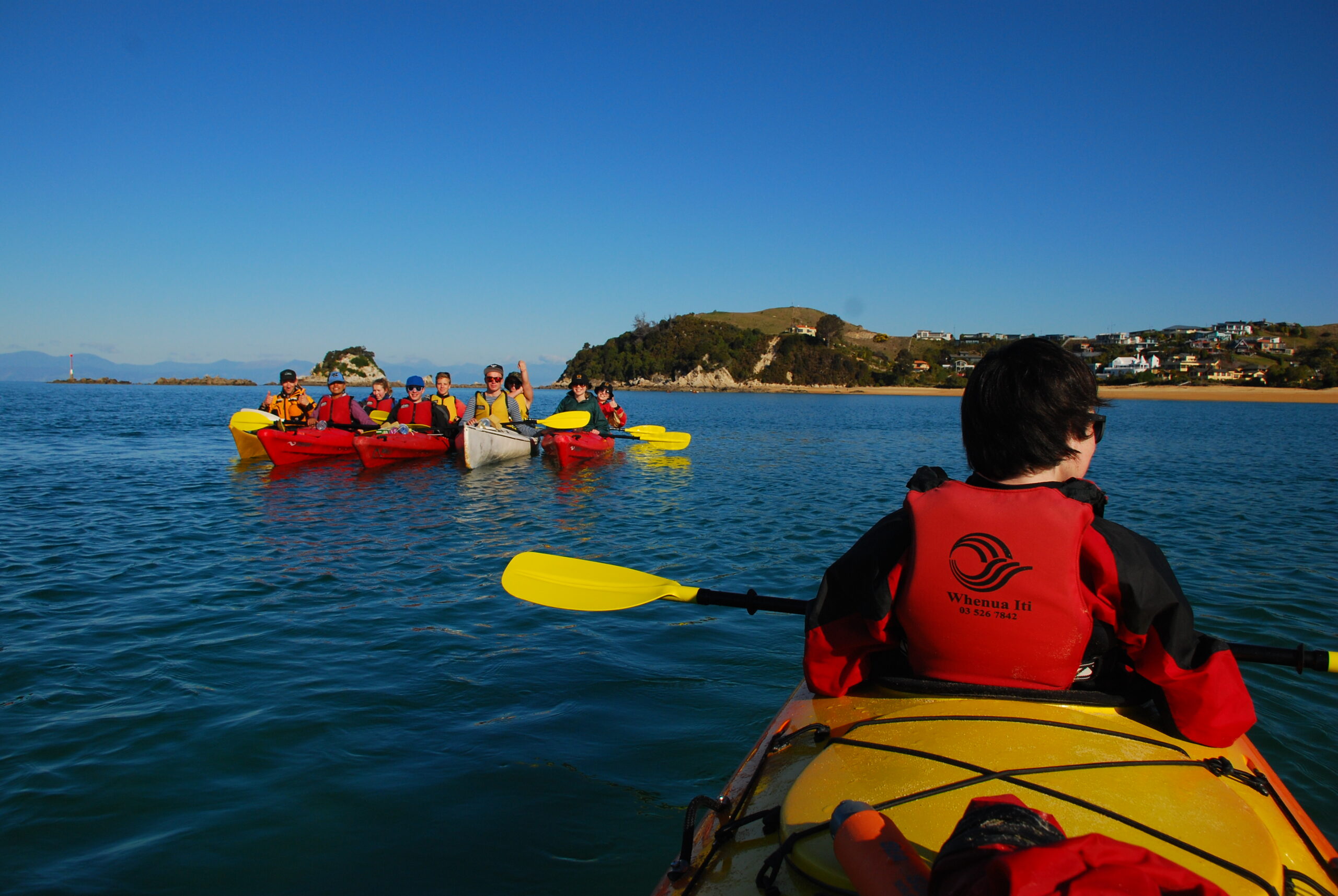 Kayak da mare che avanza lungo una costa rocciosa in una giornata invernale grigia