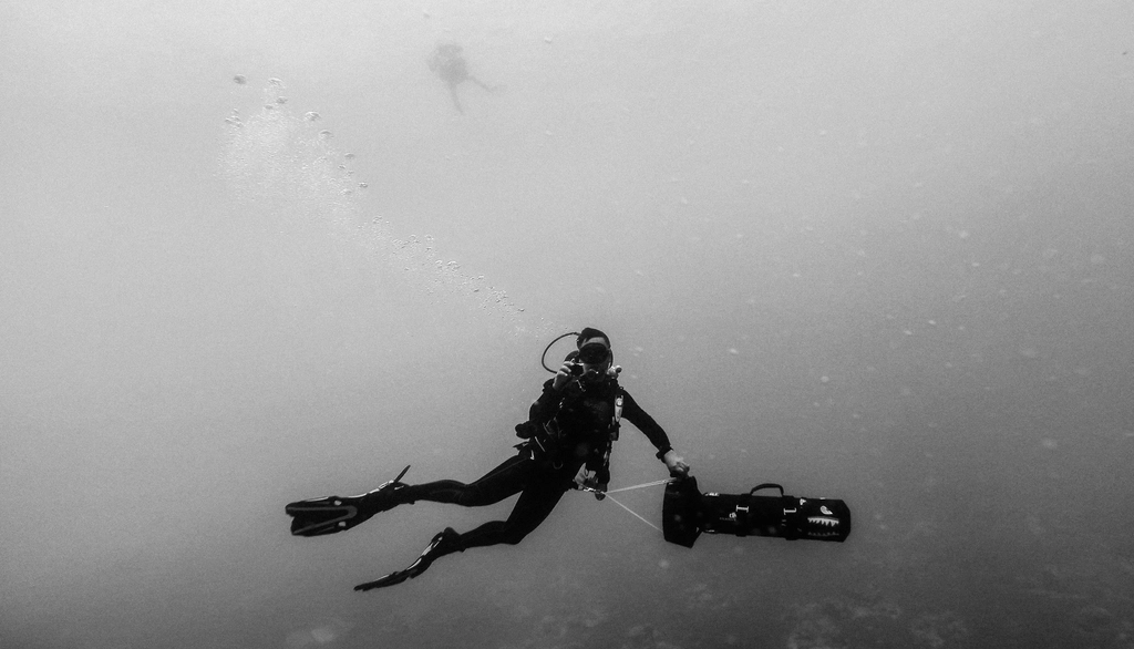 Subacqueo che taglia con cautela una rete impigliata su una parete rocciosa sommersa